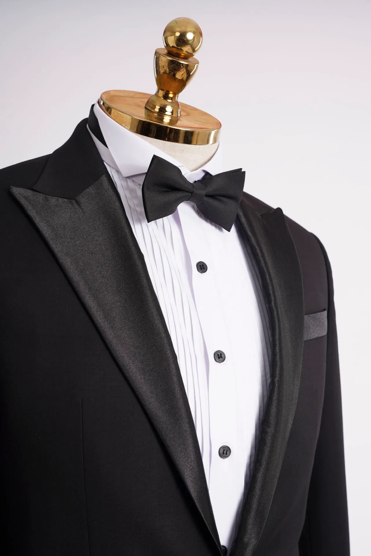 Cận cảnh ve nhọn tuxedo đen, sơ mi trắng cài khuy đen và nơ